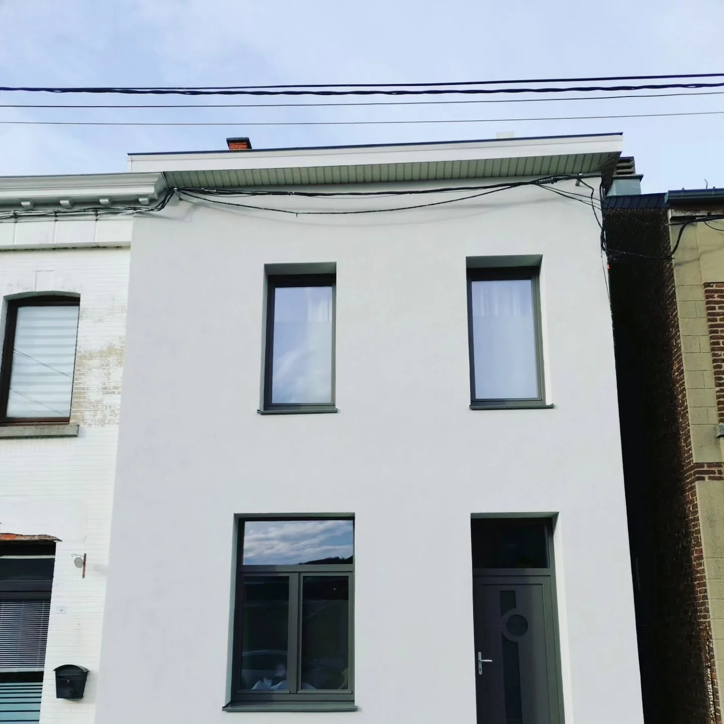 Façade Moreau rénovée, avec enduit clair et châssis foncés