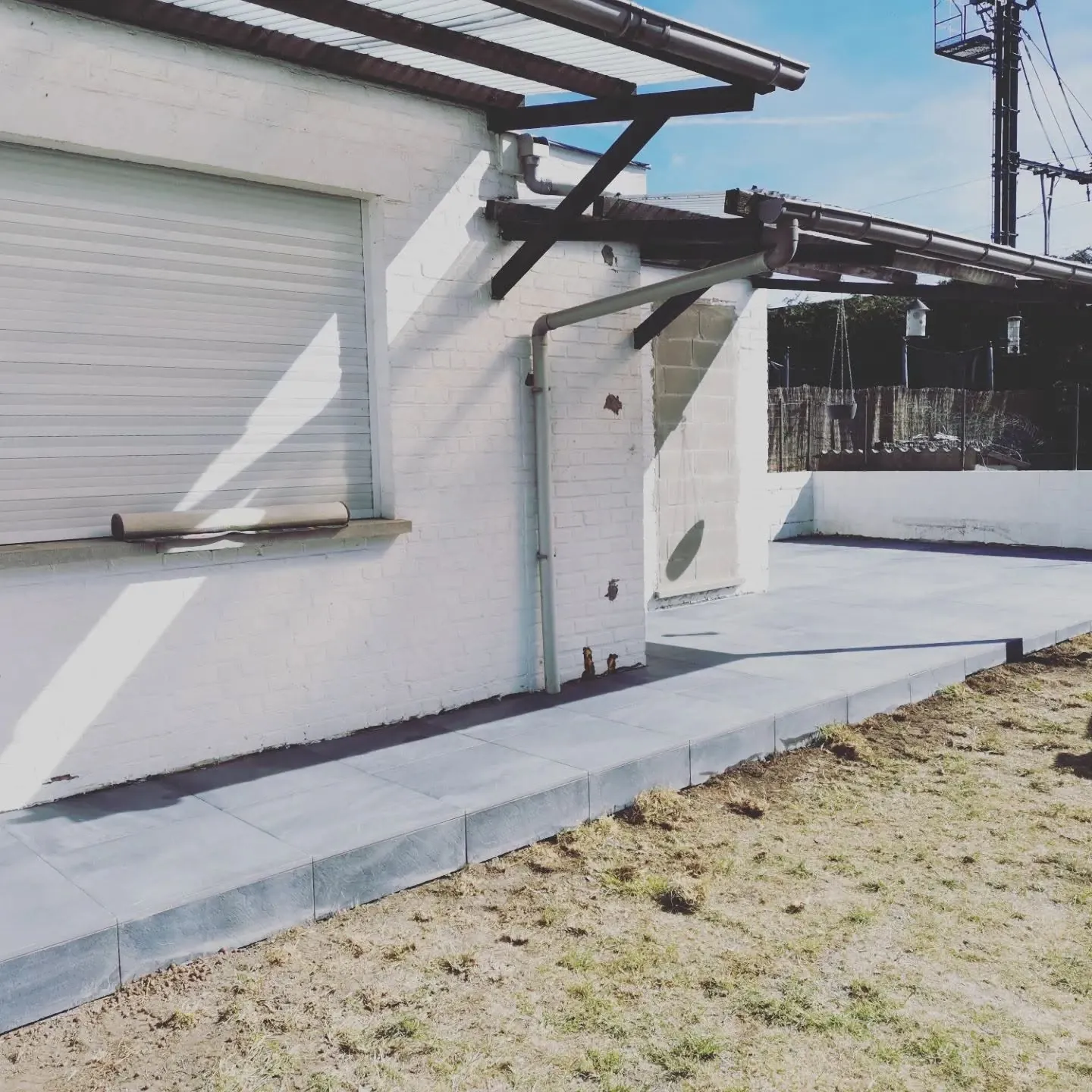 Terrasse carrelée le long de la façade et de la porte de garage