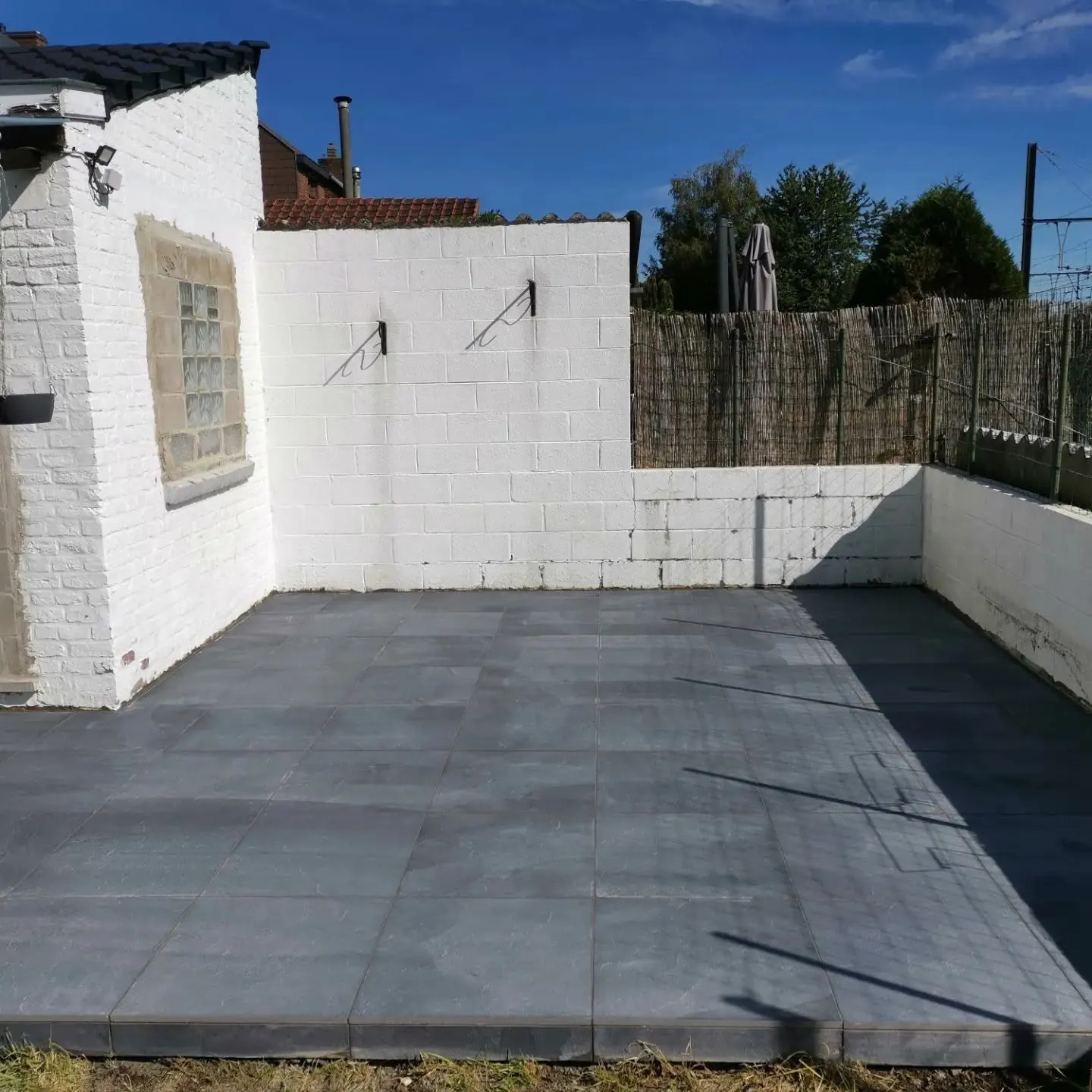 Vue générale de la terrasse carrelée grise au pied des façades
