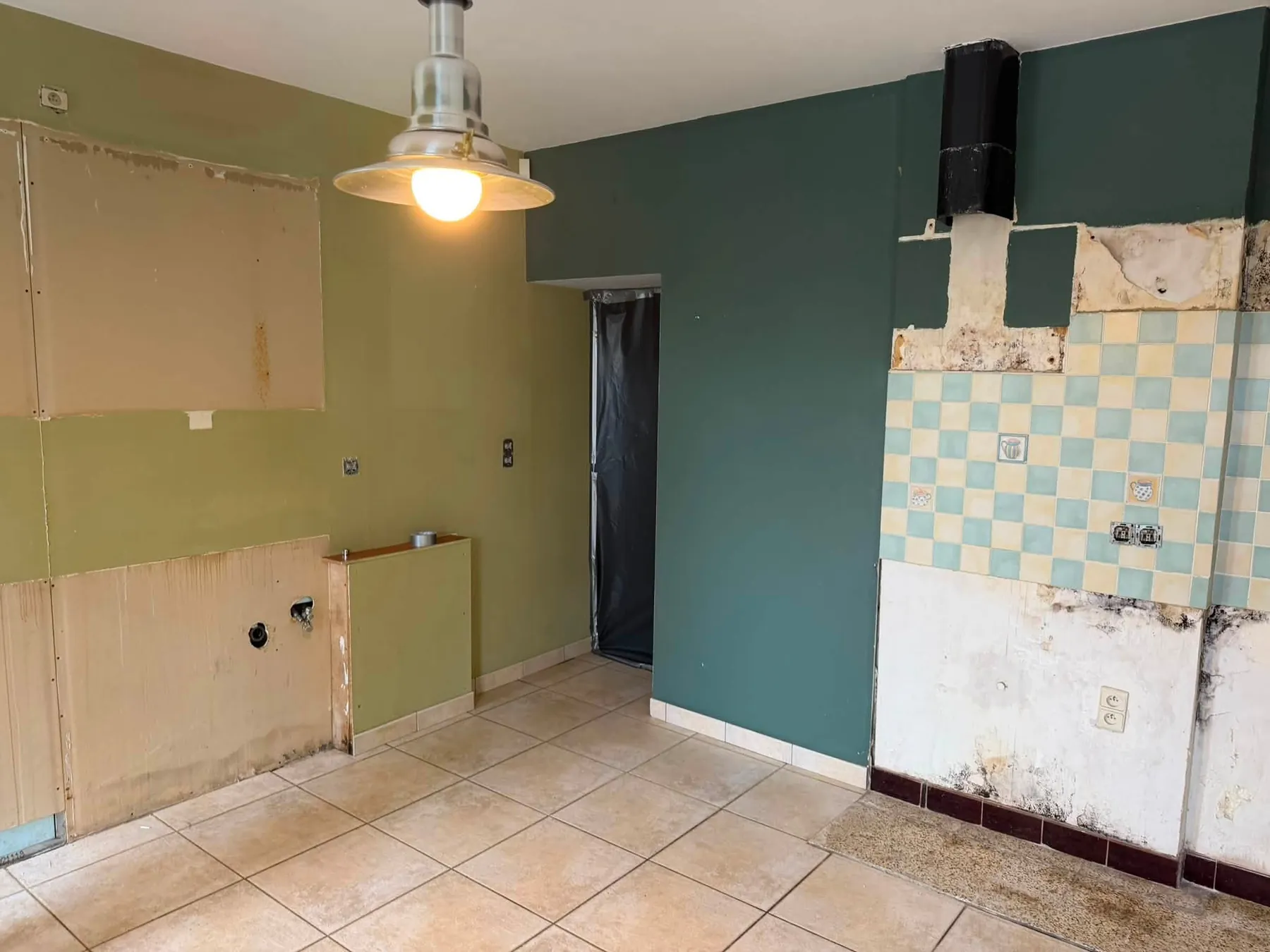 Ancienne cuisine en phase de dépose, avec carrelage mural et revêtements existants