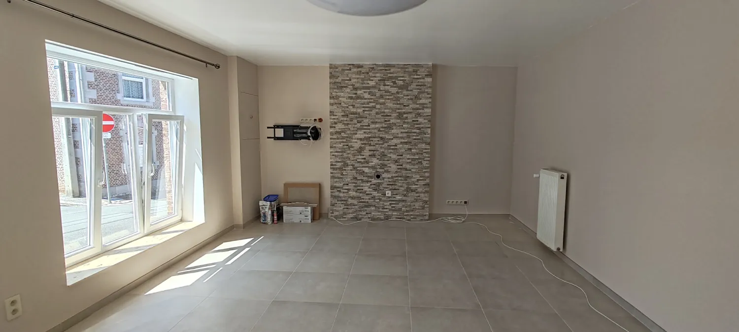 Espace de vie rénové avec grande baie vitrée, sol clair et mur décoratif