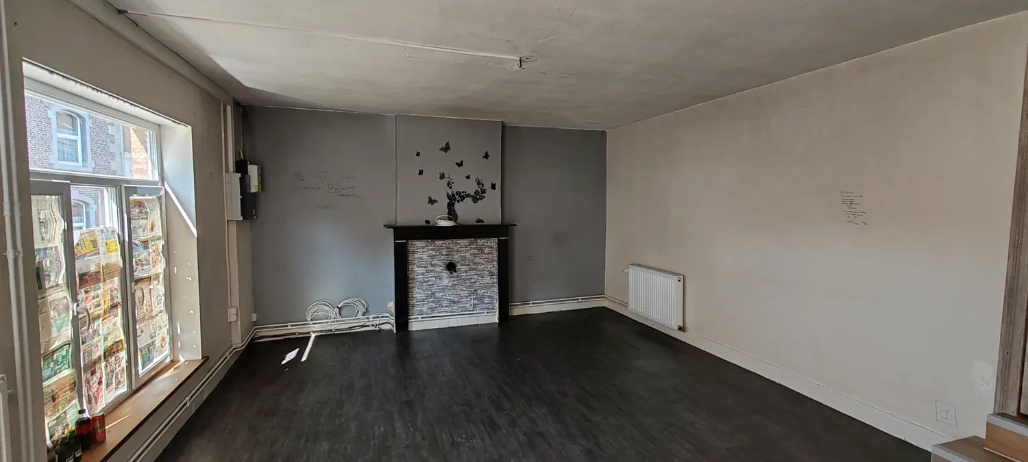 Espace de vie avant travaux avec sol sombre et grande baie vitrée